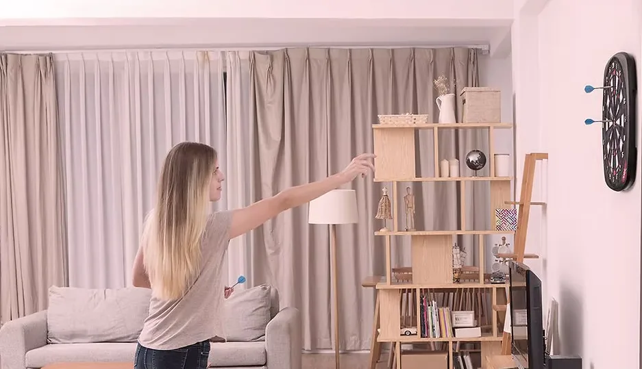 A picture of someone playing a wall-mounted electronic dartboard.