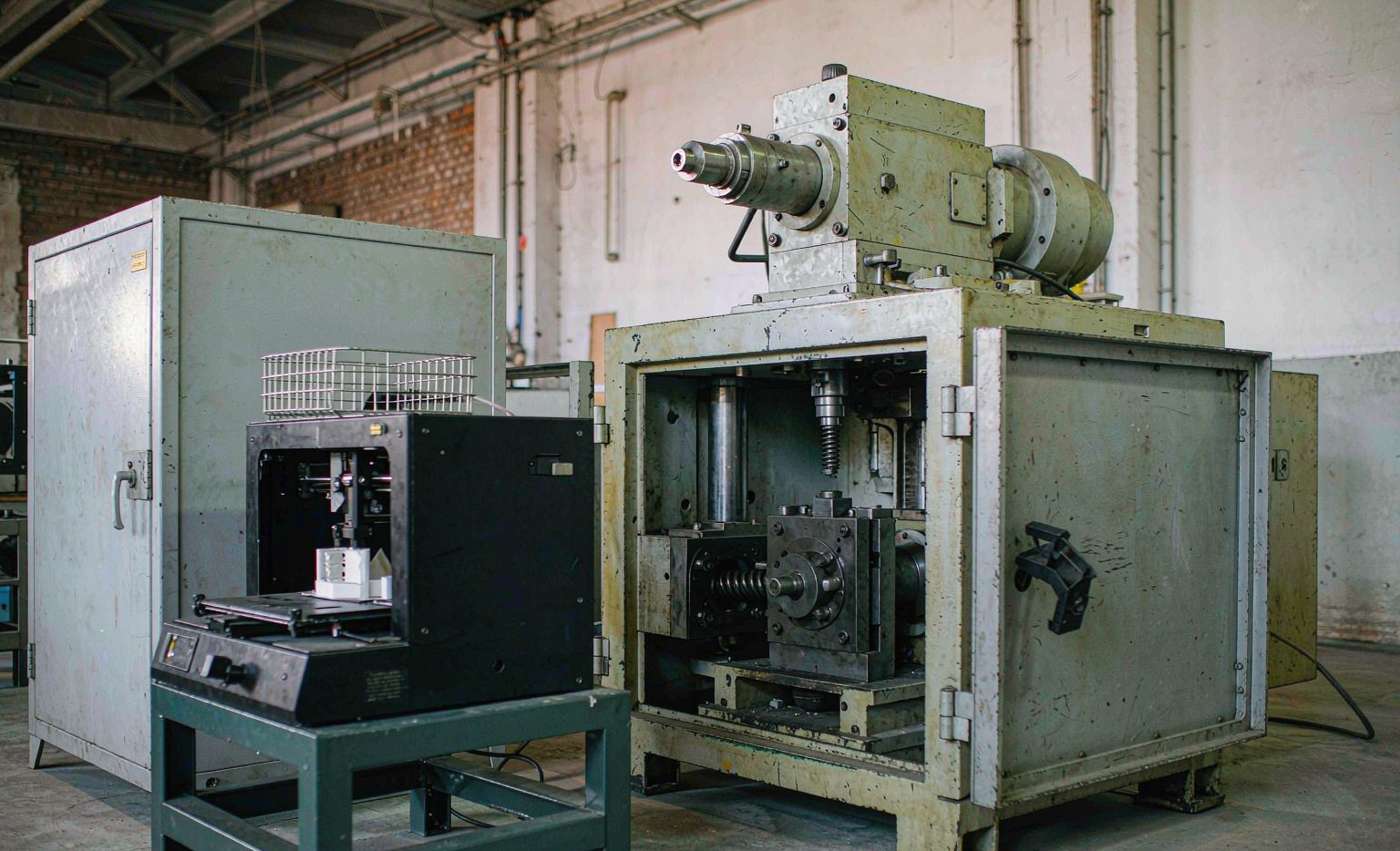 Injection molding machine beside a desktop 3D printer in a workshop
