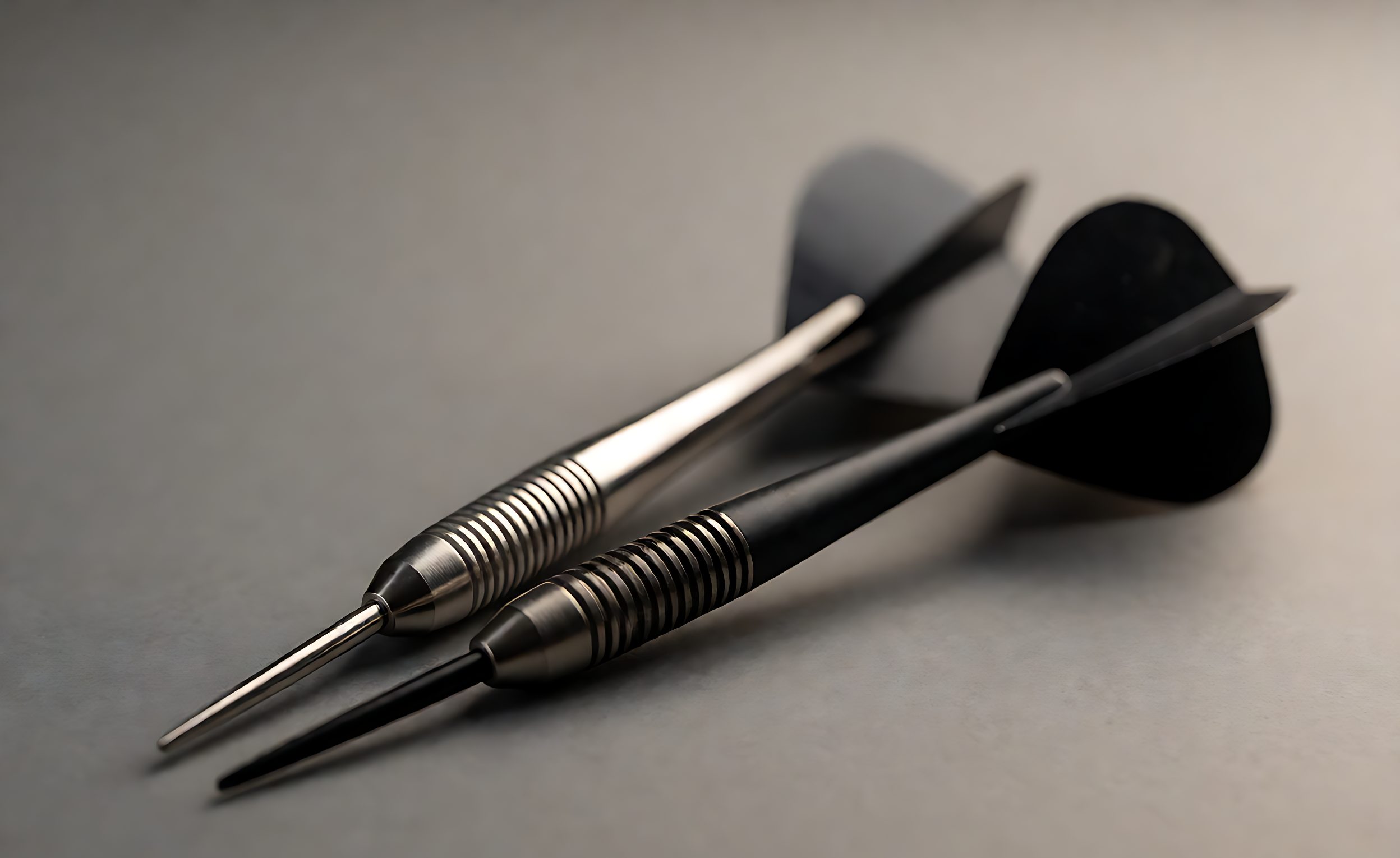 Two steel tip darts side by side, one with a metallic shaft and one with a black nylon shaft