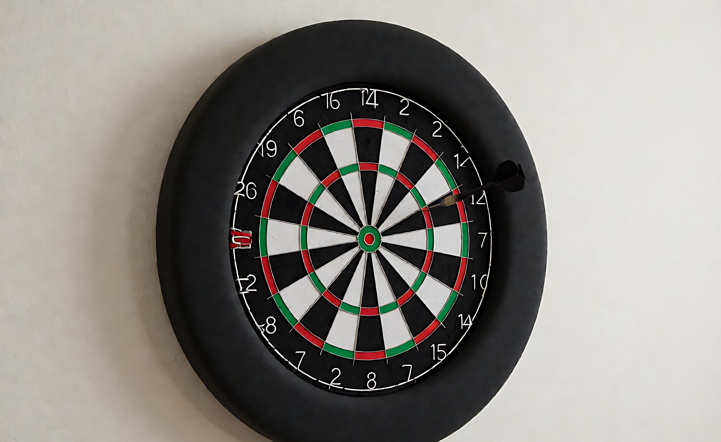 Bristle dartboard with a thick black foam surround ring fitted around it on a wall